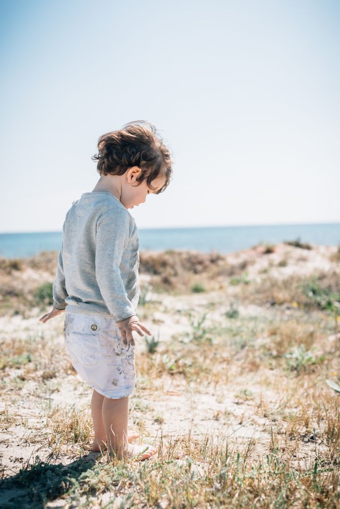 Barefoot child in short barefoot on sandy beach