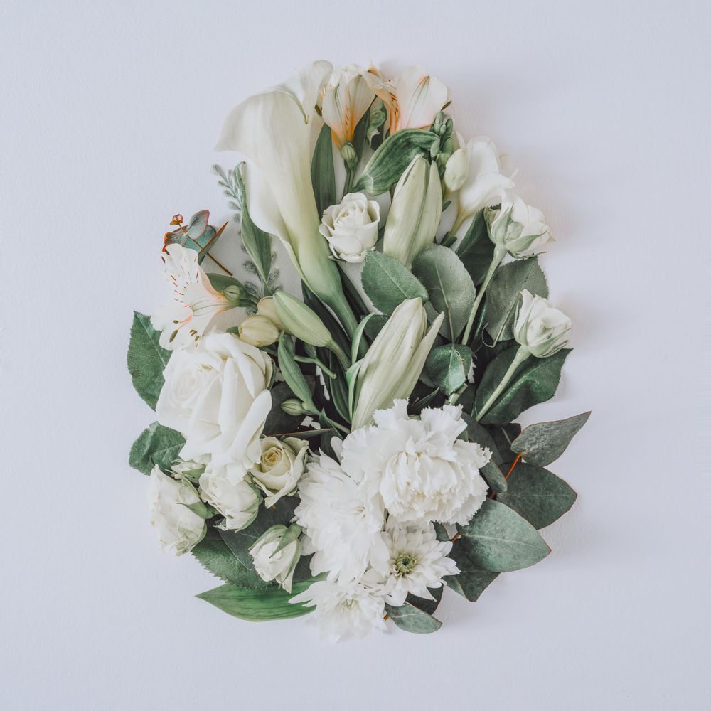Easter layout with flowers and leaves in egg shape on light  paper background