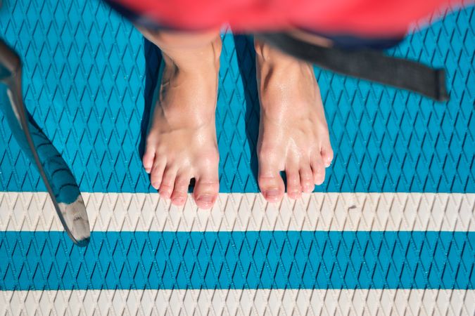 Crop barefoot person standing on SUP board