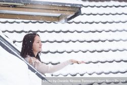 Woman reaching snowflakes through roof window 5lM9N4