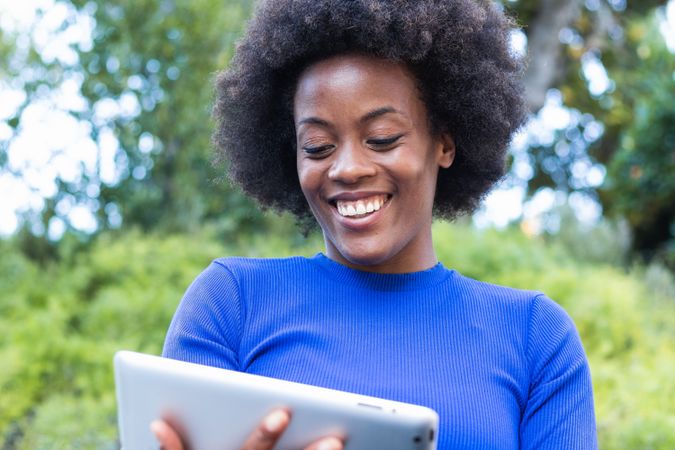Smiling Black woman browsing tablet in city