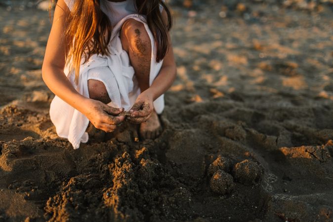 crop girl playing with sand on beach