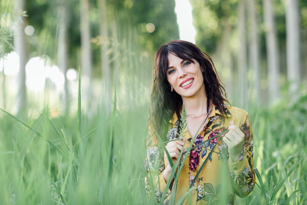 Content brunette female looking at camera in field of tall grass