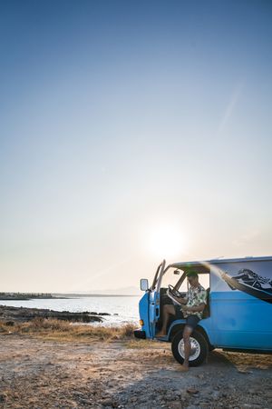 Adult man planing route for road trip while sitting in car on shore