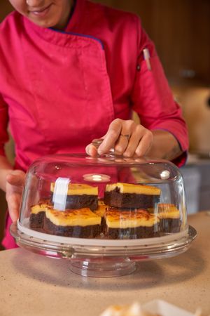Crop woman serving sliced dessert on glass stand