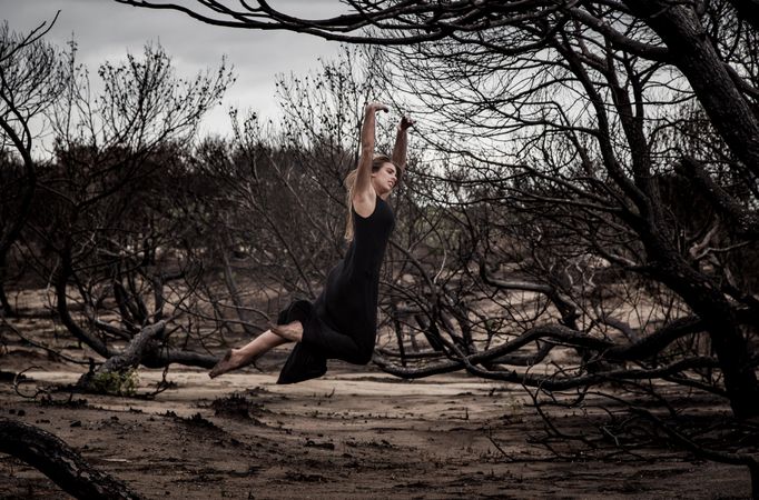 Woman dancing between dry trees