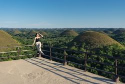 Happy woman standing on observation deck on hill