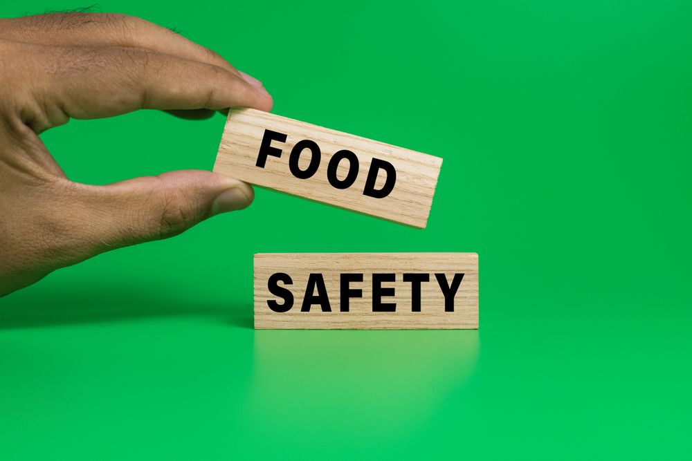 male hand put wooden blocks with food safety words text isolated on green background