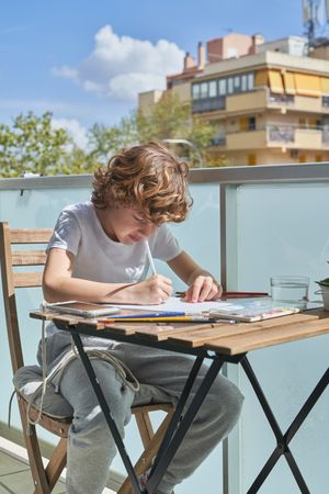 Boy painting at table on balcony