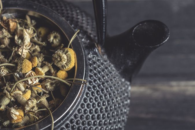 Spoonful of dried chamomile on brass teapot