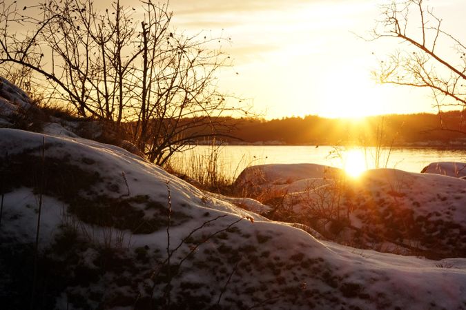 Rocky peaceful shore with snow crust in sunrays