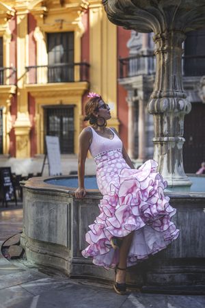 Joyful woman in flamenco dress dancing on street