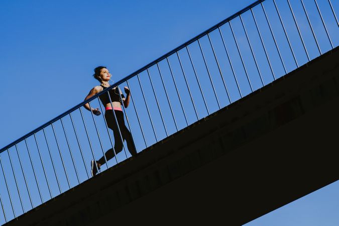 Woman running on walkway in sunny day with blue sky