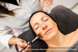 Woman having facial product brushed on face 4jVOlW
