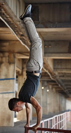 Male doing handstand on a handrail in garage