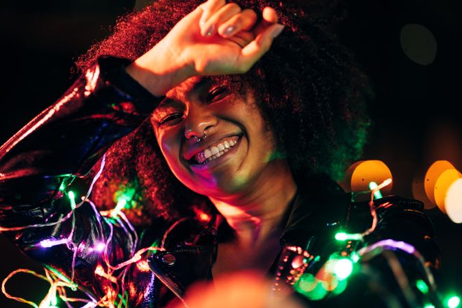 Smiling Black woman at night lit by neon lights
