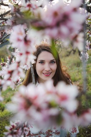 Young happy woman between trees in garden