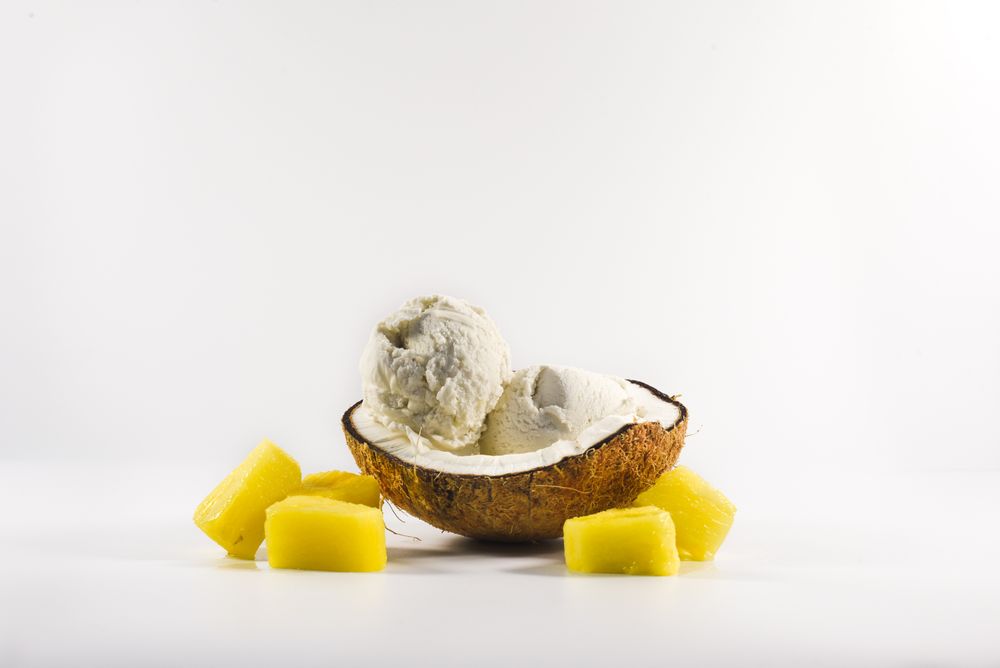 Coconut shell with scoop of pineapple ice cream and fruit chunks