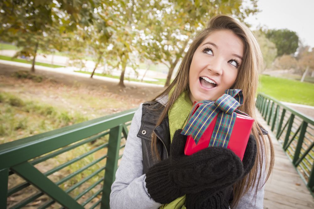 Happy Woman with Wrapped Gift with Bow Outside