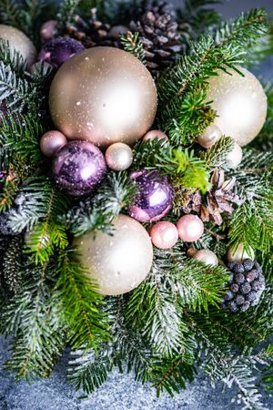 Close up of purple and gold Christmas centerpiece in pine branch