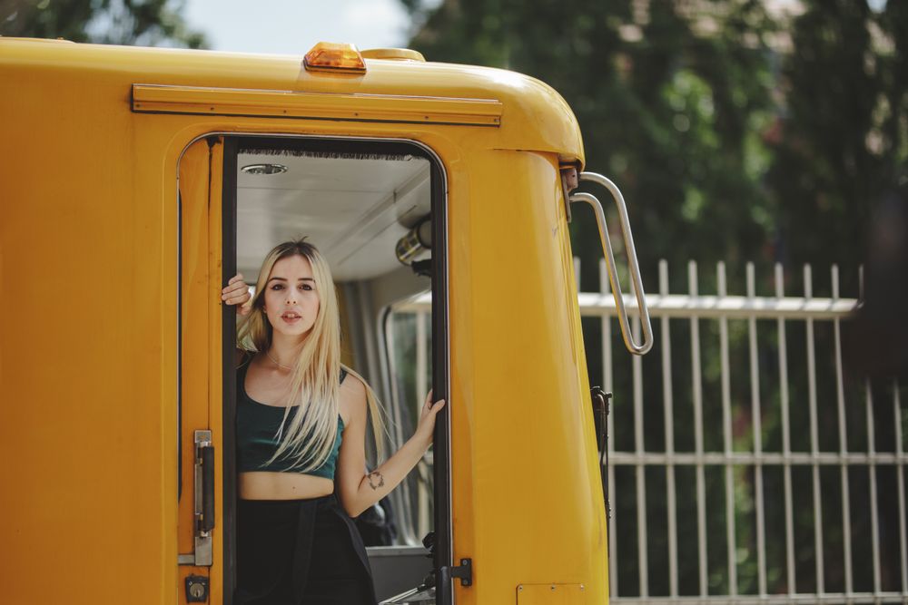 Cheerful blonde woman standing on train in drivers cabin