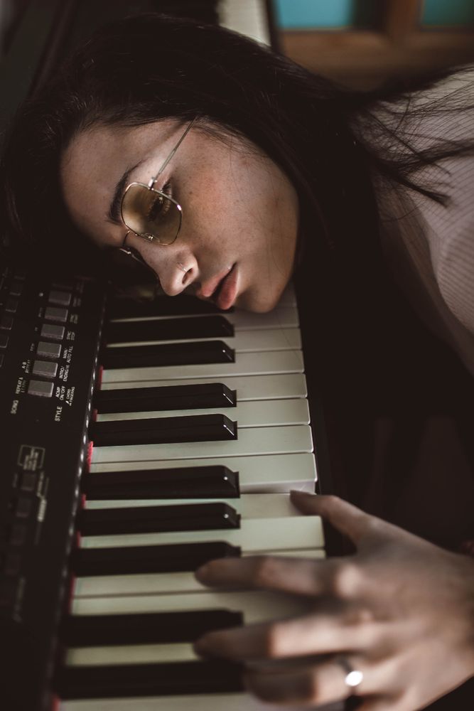 young woman with her head resting on the piano