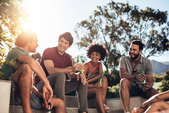 Young group of friends enjoying drinks together outdoors