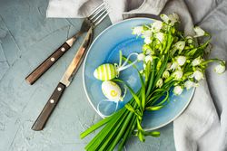 Top view of table setting for Easter dinner with egg decor and flowers with space for text