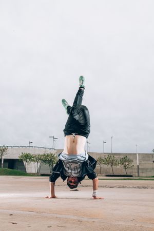 Skillful break dancer performing handstand while moving
