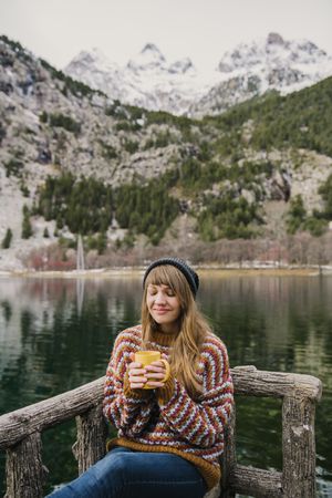Woman on seat near wonderful lake between hills in snow
