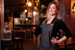 Cheerful waitress holding tray with wineglasses