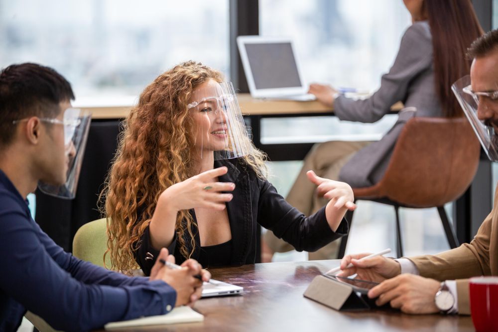 Woman leading meeting office wearing a face shield