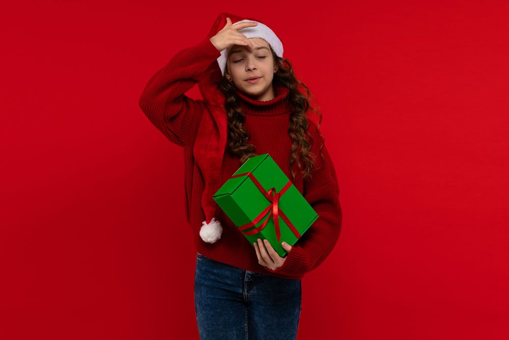 Young girl in Santa hat holds green gift box