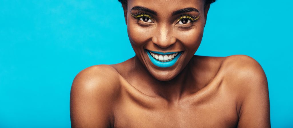 Close up of smiling woman with vibrant makeup against blue background