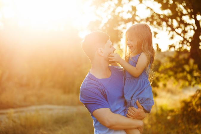 Man lifting daughter in sunny field