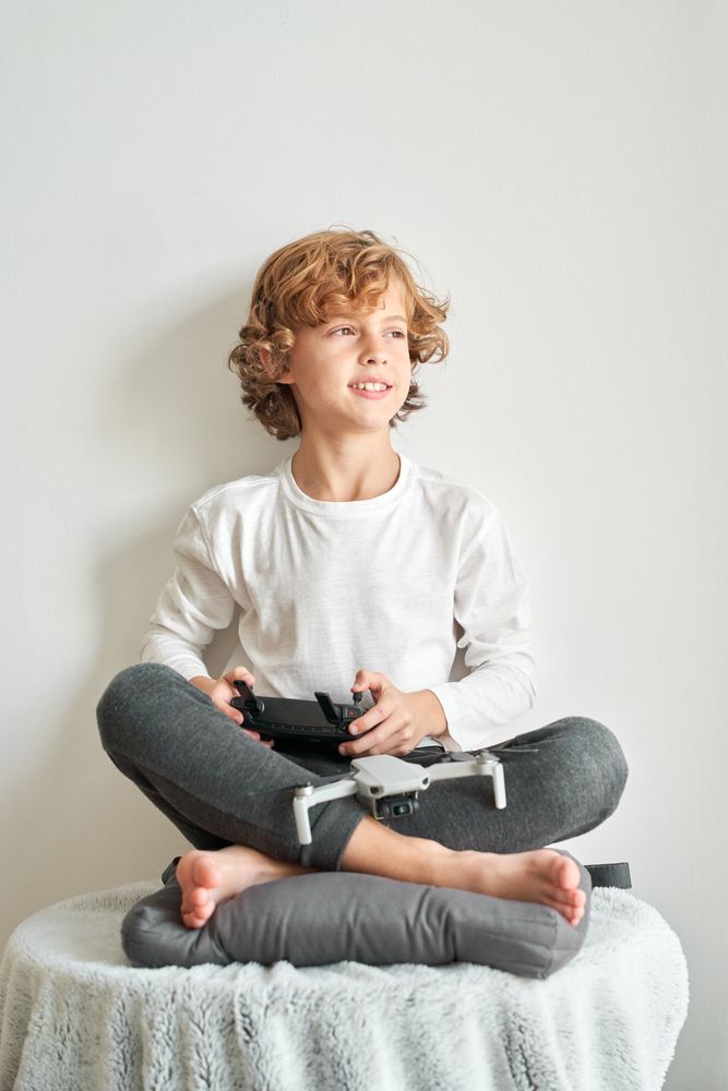 Dreamy preteen boy with drone and console of remote controller