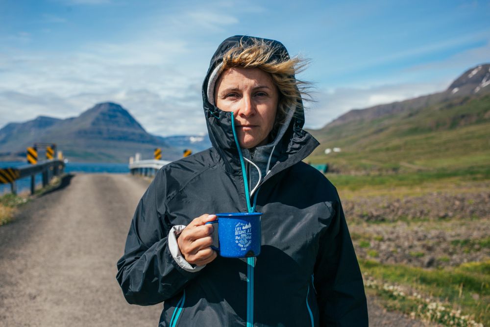 Woman with ceramic mug near rural bridge