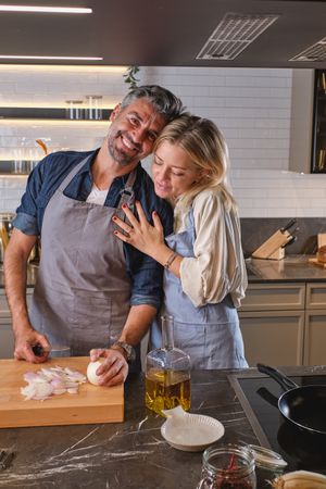 Content couple cutting onion in kitchen