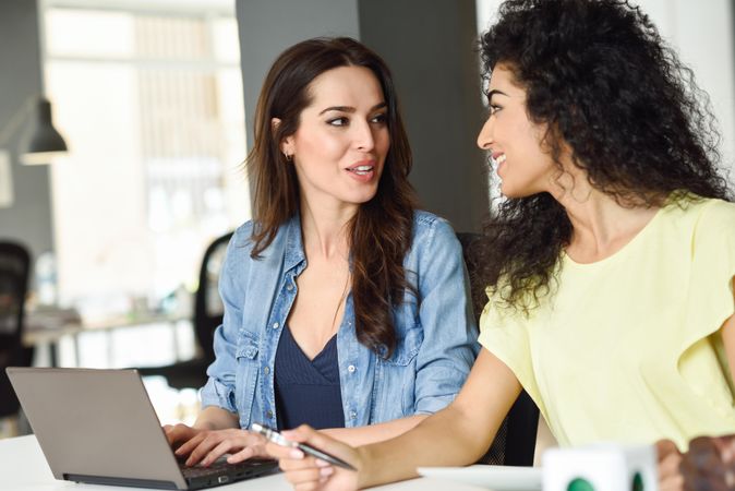 Two women discussing work project over laptop