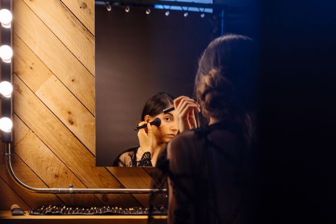 Beautiful brunette female in peignoir applying makeup