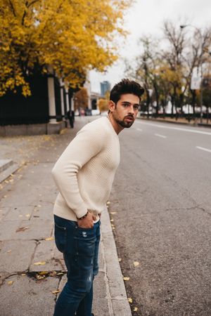 Young male looking for car on roadside