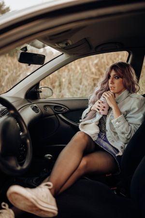 Stylish woman having drink in car