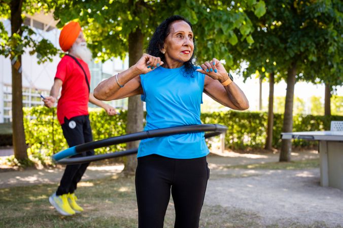 Mature Sikh couple hula hooping and jumping rope in park