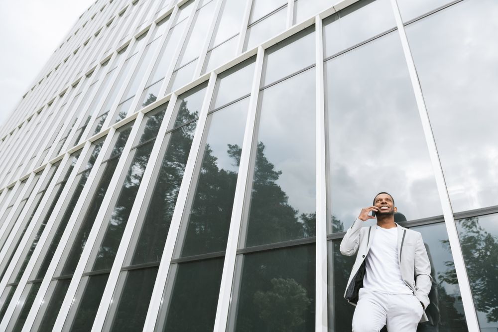 Elegant Black man talking smartphone leaning building