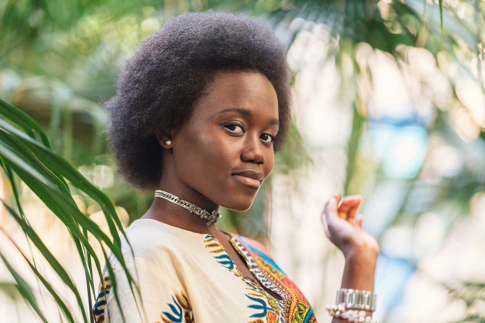 Cheerful Black woman amidst palm leaves