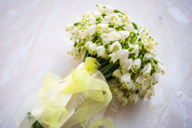 Snowdrop bouquet wrapped in yellow ribbon on table