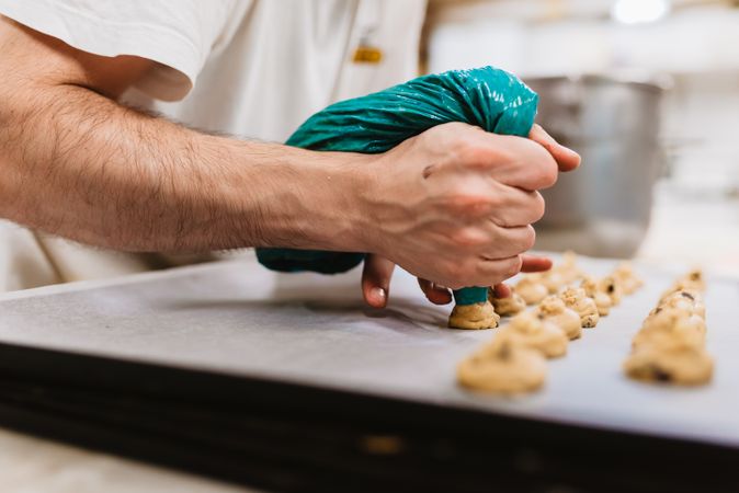 Crop baker squeezing dough on tray