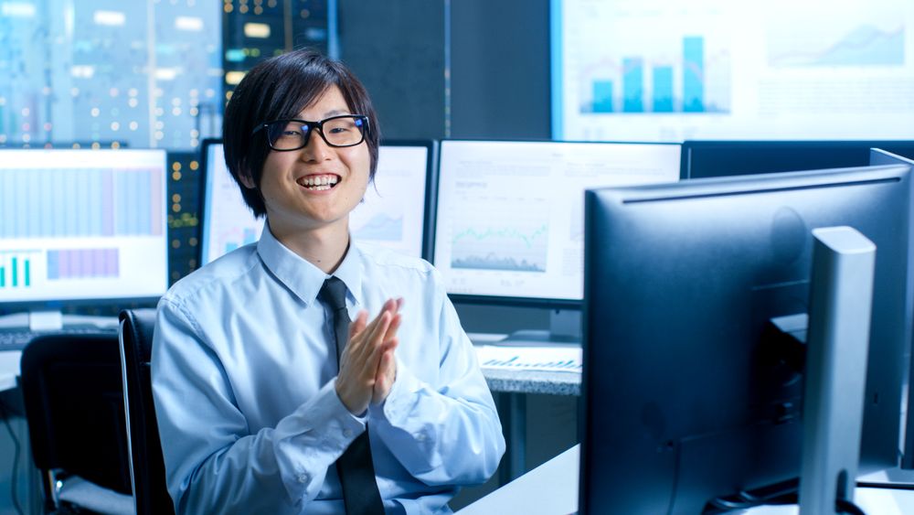 In the Data Mining Center Statistician Claps His Hands while Sitting at His Workstation Surrounded with Monitors Displaying Data and Graphs.