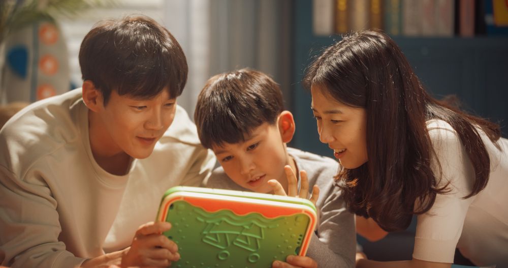 Idyllic Young South Korean Family Spending Leisure Time Together at Home, Watching Cartoons Online