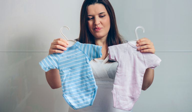 Pregnant woman choosing baby bodysuits